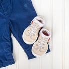 Blue corduroy pants and baby booties on a white wood surface.