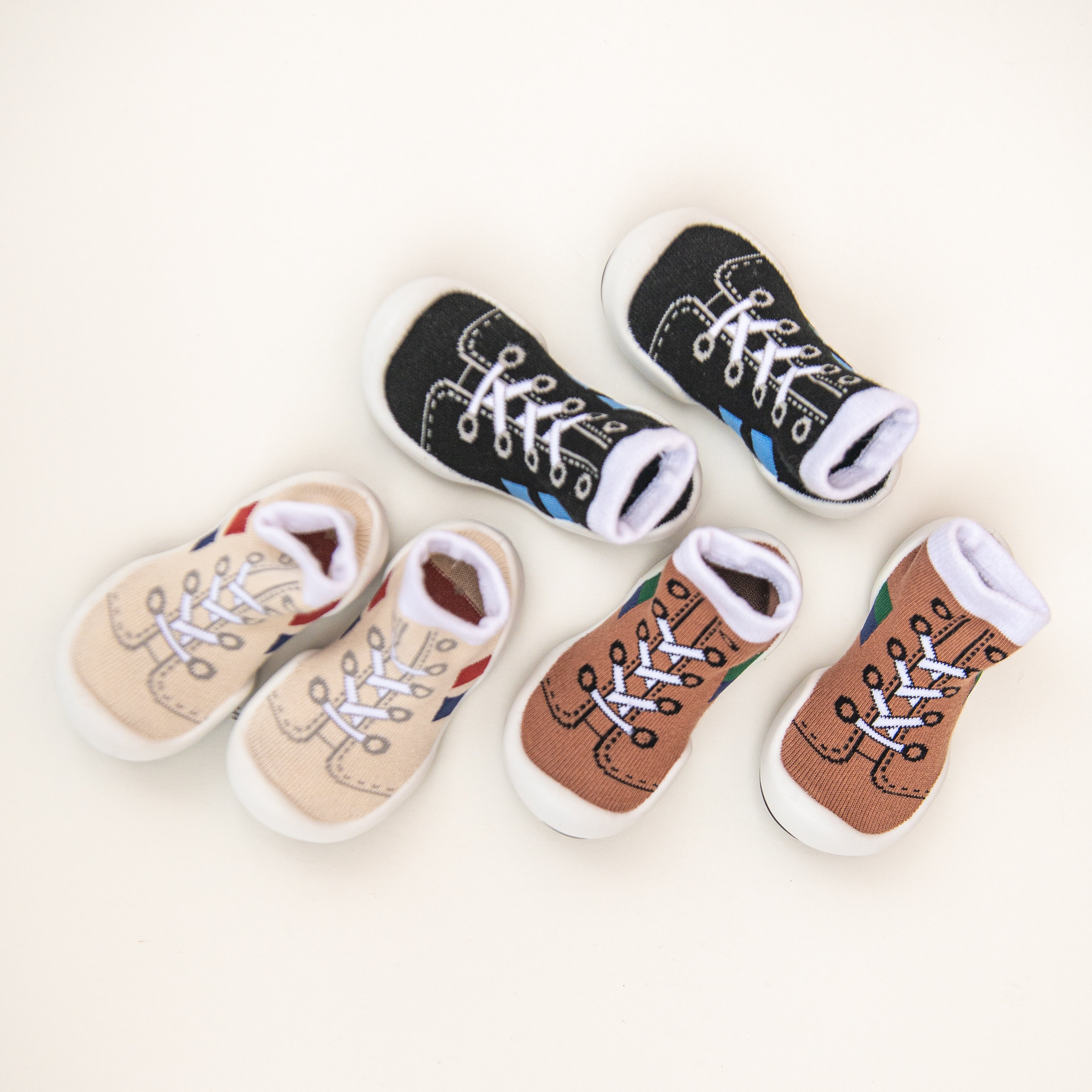 Three pairs of baby sock shoes: black, tan, and brown.