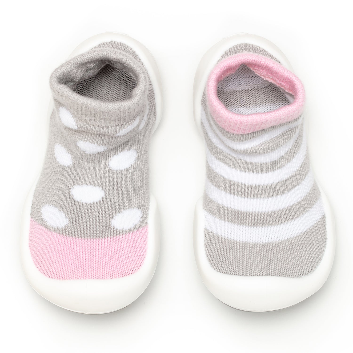 Two baby socks with a white sole. The sock on the left is gray with white polka dots and a pink toe. The sock on the right is gray and white stripes with a pink upper trim.