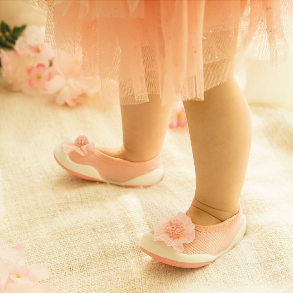 Baby's legs and pink flower-embellished shoes.