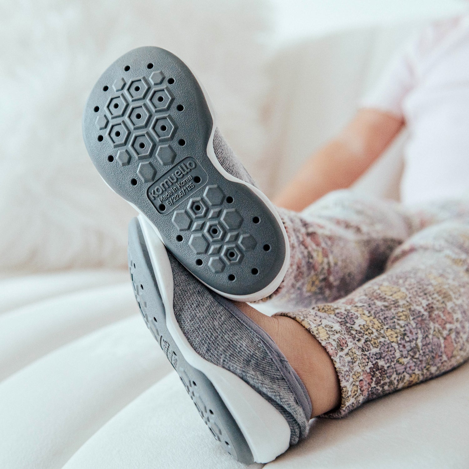 A child resting with gray-soled slippers.