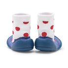 Rear view of a pair of baby sock shoes.  White sock tops with red polka dots lead into blue rubber soles.  Set against a white background.