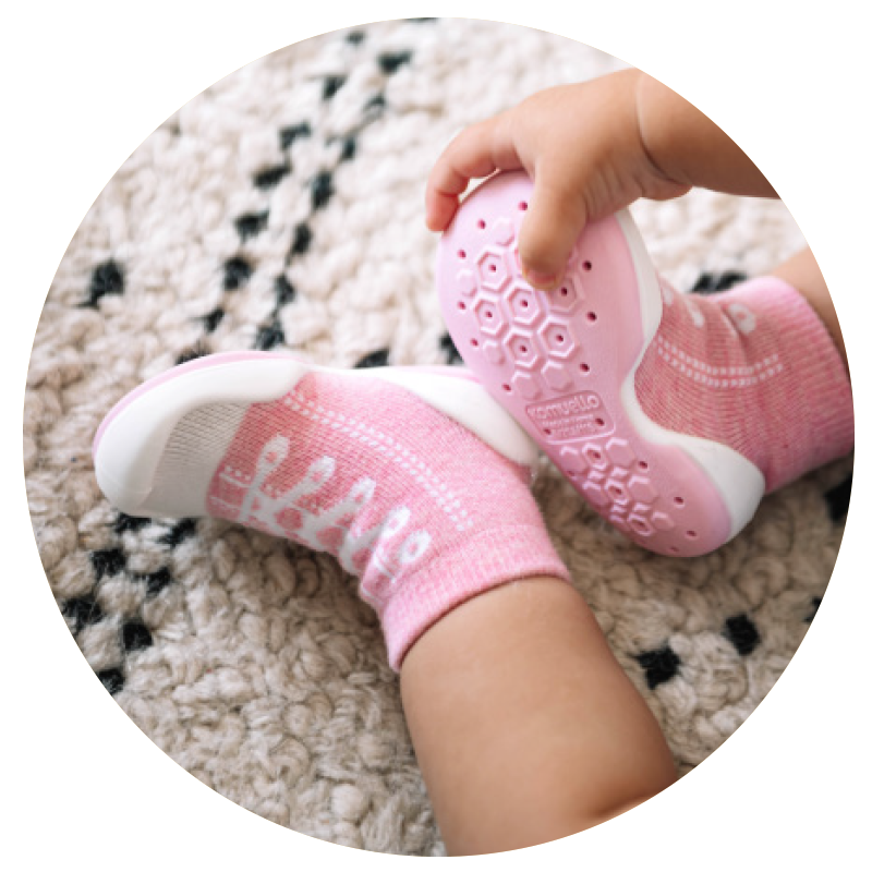 Infant wearing pink Sneakers Komeullo sock shoes with white soles.