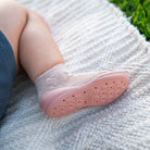 Child's foot in sock and pink shoe.