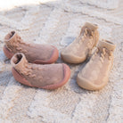 Two pairs of baby shoes on a textured rug.