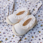 Two baby shoes with lace trim on a floral patterned garment.