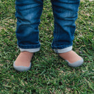 Child's legs in jeans and sock-shoes on grass.