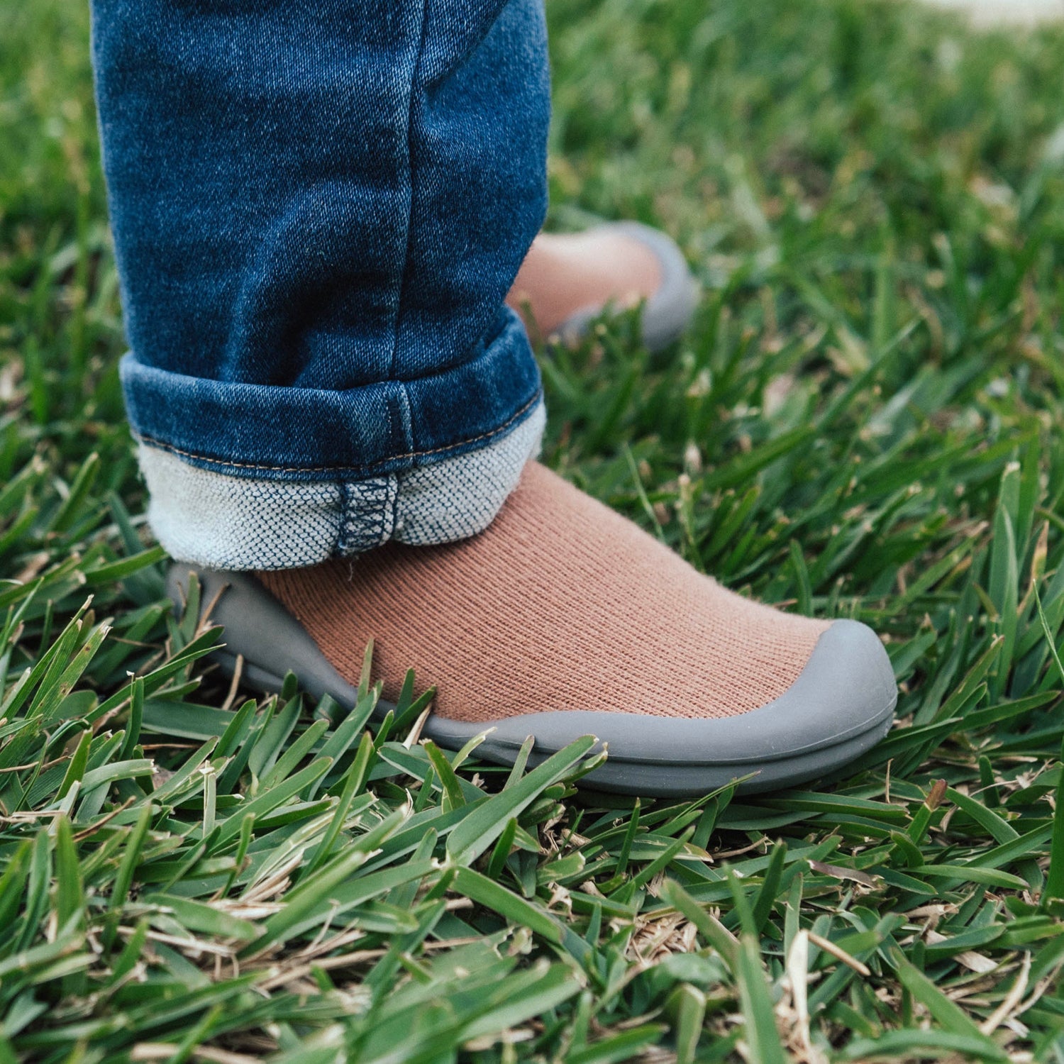 Blue jeans, brown sock shoes, green grass.