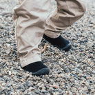 Tan pants and black slip-on shoes on gravel.