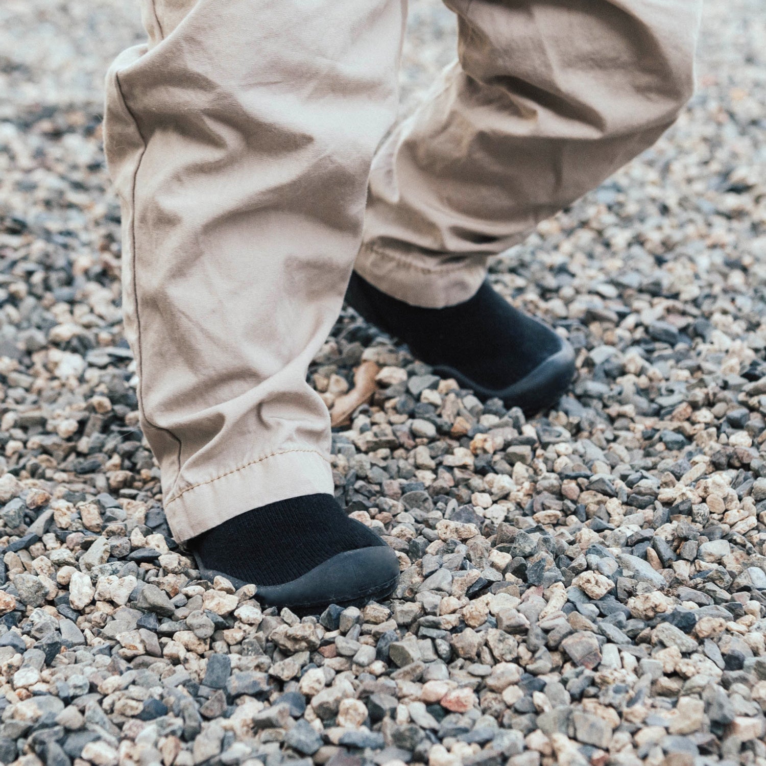 Tan pants and black slip-on shoes on gravel.