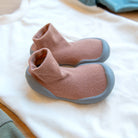 Two brown sock shoes with gray soles on a white shirt.
