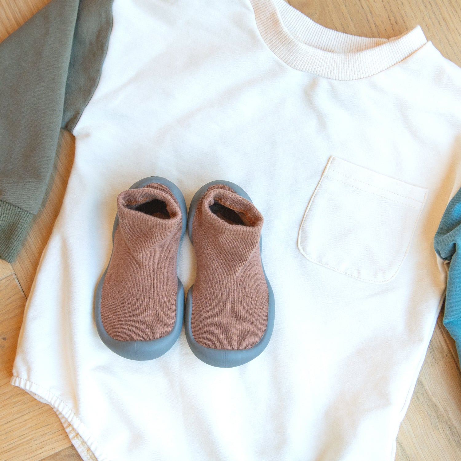 Baby onesie with two-toned sleeves and sock-shoes.