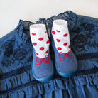 Blue denim dress with ruffled trim, paired with white and red polka dot socks with blue shoe coverings.