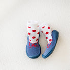 Two baby shoes with socks on white woven fabric.