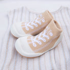 Beige and white baby shoe-socks on a striped shirt.