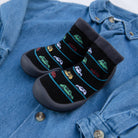 A pair of black socks with car patterns on a blue denim shirt.
