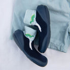 Navy blue shoes with dinosaur socks on light blue shorts.