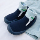 A pair of blue baby sock shoes with dinosaur accents.