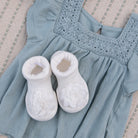 Baby dress and booties, light blue with white accents.
