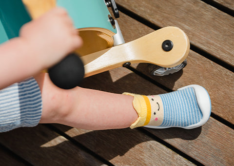 Child's foot wearing a Komuello Prince shoes on a wooden floor