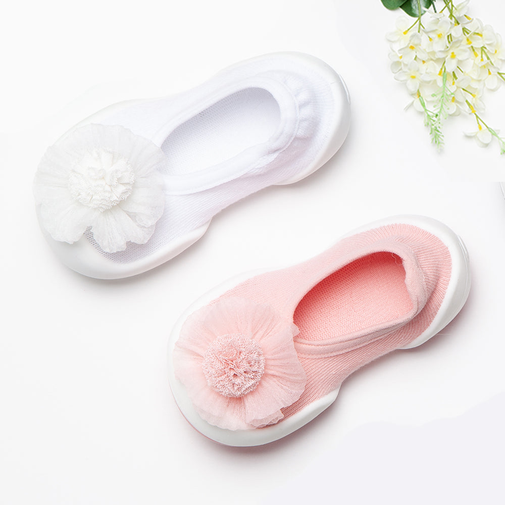 Close-up of a pair of white and pink baby socks with floral decorations.