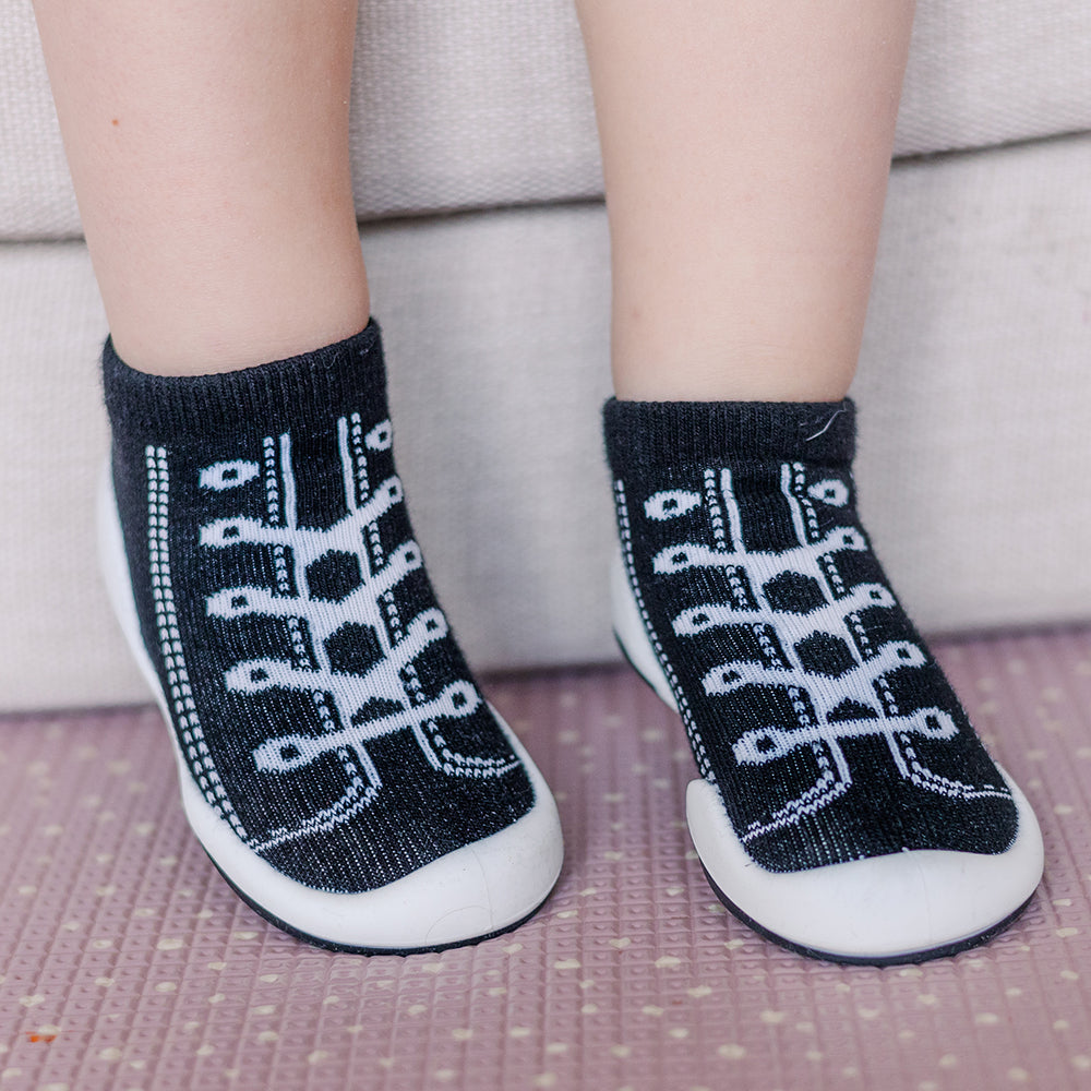 Baby's feet wearing black and white sneaker socks.