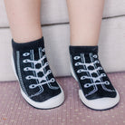 Baby's feet wearing black and white sneaker socks.