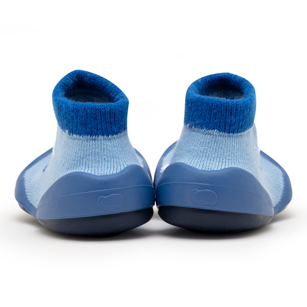 Back view of a pair of blue baby sock shoes on a white background.