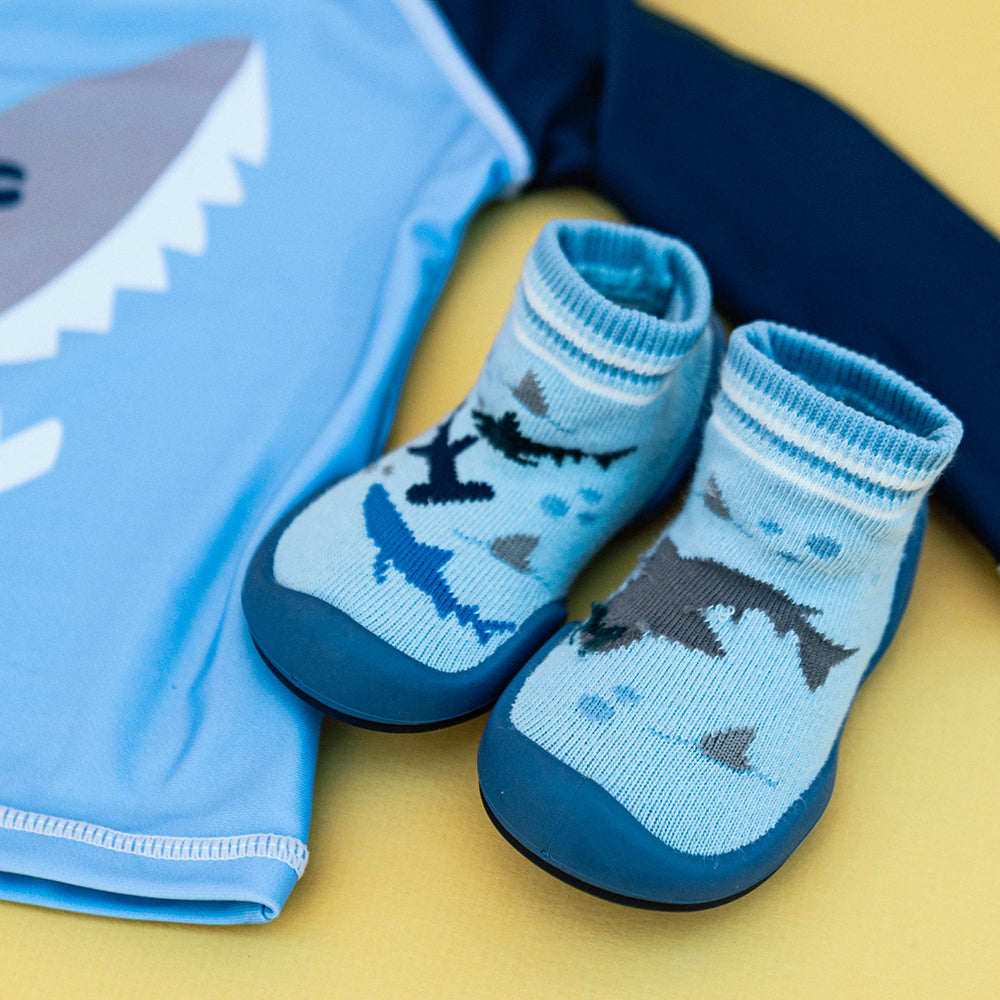 Shark-themed baby slippers and shirt with a shark face.
