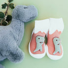 Stuffed dinosaur toy, pair of dinosaur baby socks on a green background.