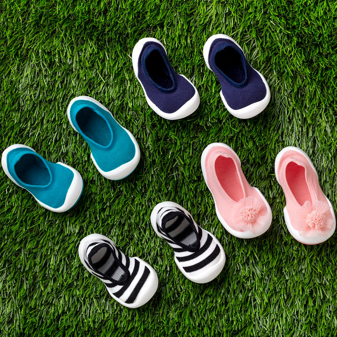 Eight baby socks-shoes on green grass.