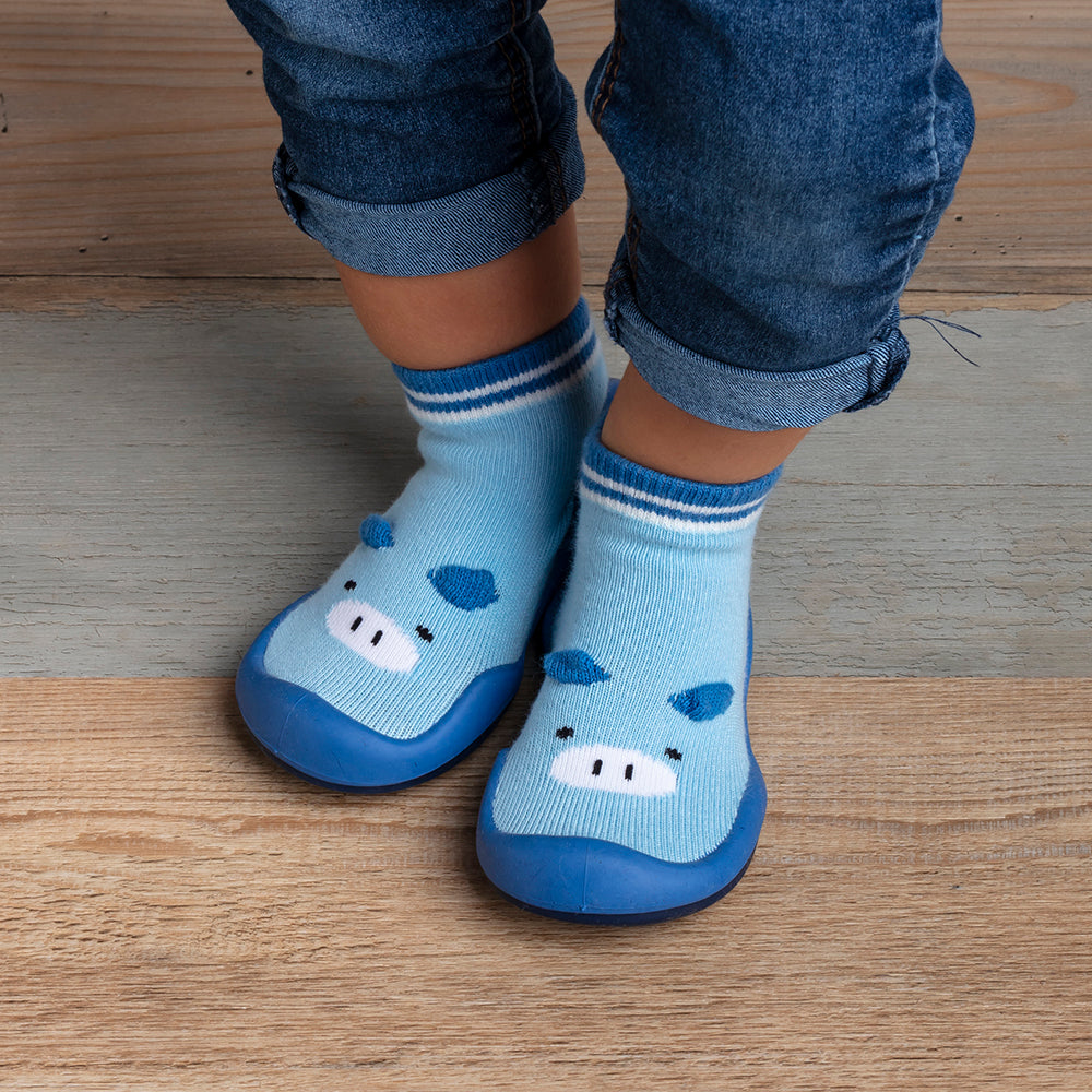 Baby wearing blue hippo slipper socks and denim pants.