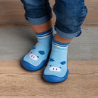 Baby wearing blue hippo slipper socks and denim pants.