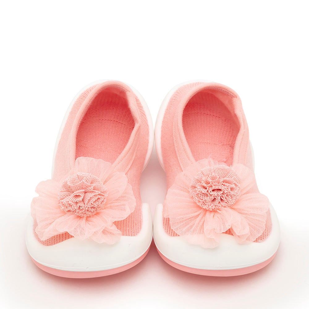 Pair of pink baby shoes with white soles and a flower decoration.