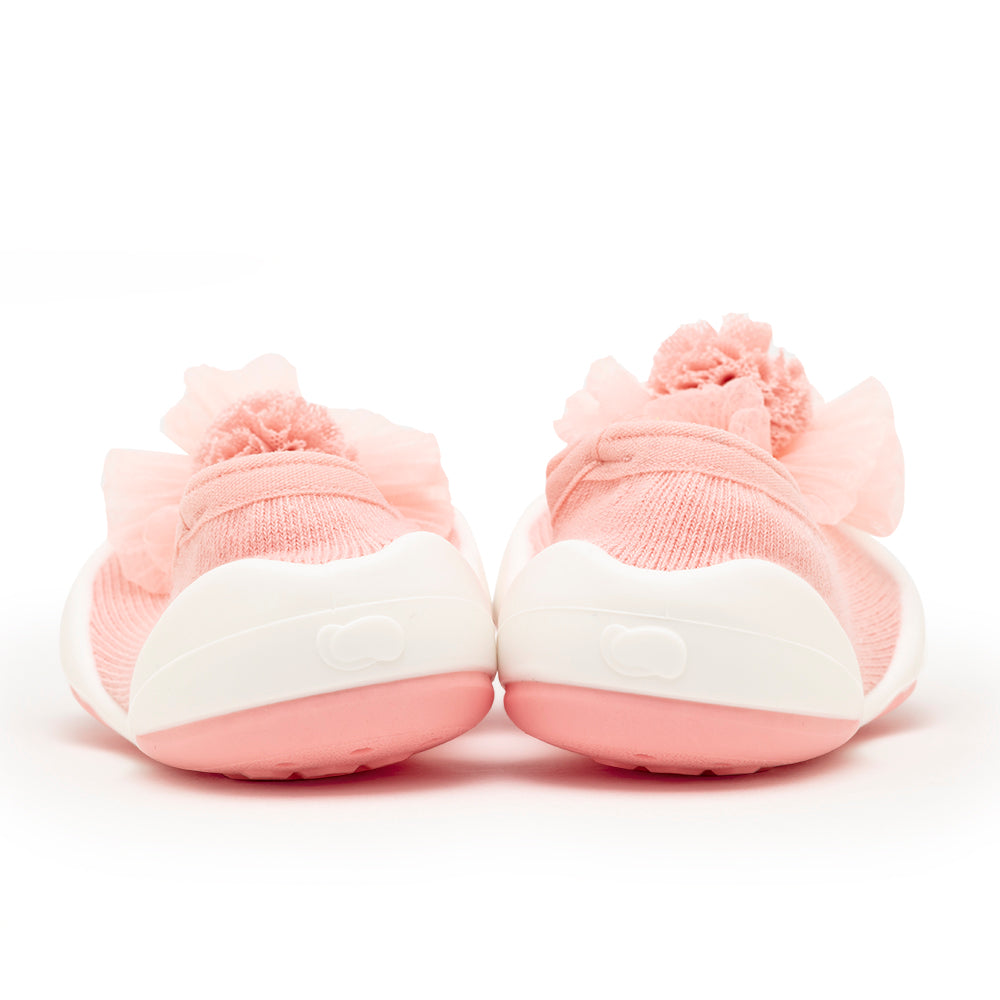Close-up of pink baby shoes with pom-poms.