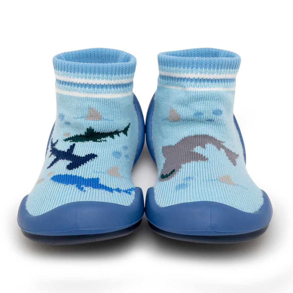 Two blue toddler sock shoes with shark and dolphin patterns.