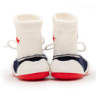 Back view of white sock shoes with red soles and navy blue trim.