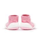 Pink sock baby shoes with white soles, back view.