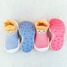Two pairs of toddler sock shoes, one blue and one pink, arranged on a white textured surface.