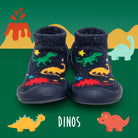 A pair of dinosaur-patterned sock-shoes on a green background with dinosaur illustrations.
