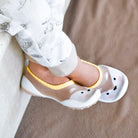 Baby wearing animal-patterned sock shoes and patterned pants.