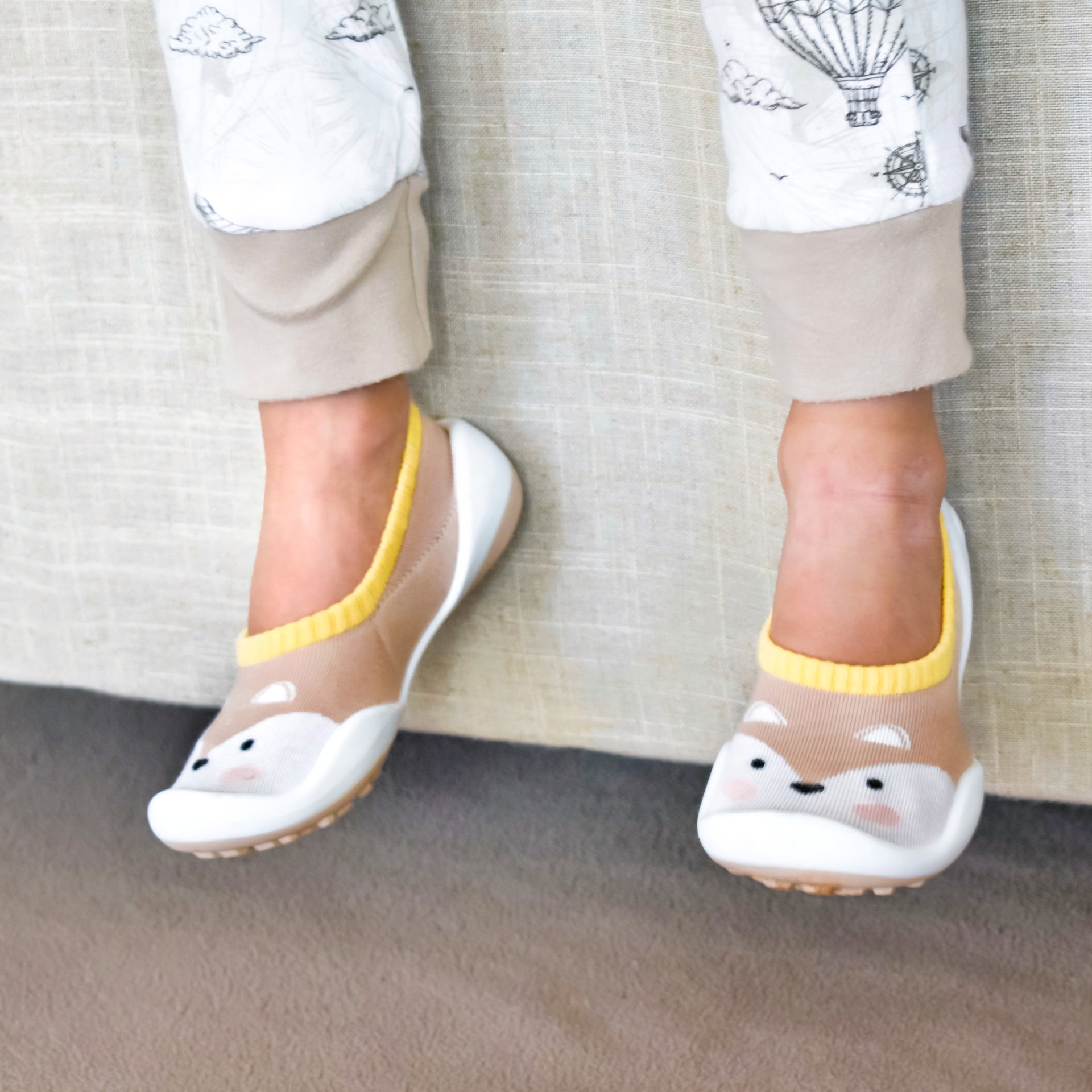 A child's feet wearing fox-themed slipper socks.