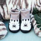 Two baby socks with a tiger face design, against a plush, striped backdrop.