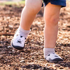 Baby wearing grey socks and white bear print shoes.
