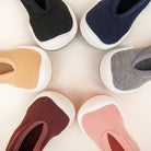 Six colorful, soft baby shoes arranged in a circle.
