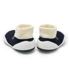 Two baby sock-shoes with cream-colored sock tops, black uppers, and white soles.