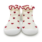 Two baby shoes with red heart pattern and ruffled red trim.
